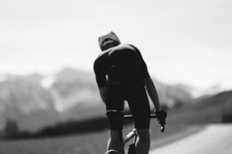 Road bike rider in spring in the Allgäu against the picturesque backdrop of the Alps, Bavaria,