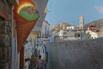 Narrow alleyway view in the colourful Mediterranean village of Olymbos with church tower in the