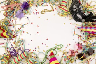 Colourful carnival paraphernalia such as hats, masks and confetti on a white background