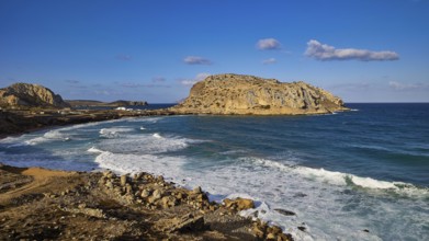 Rocky coastal landscape with blue sky and crashing waves, Acropolis Hill, Arkasa, West Coast,