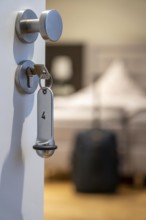 Symbolic image of a hotel, key inserted in the door of a hotel room, analogue lock