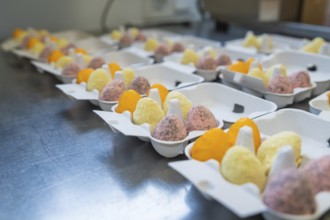 Colourful egg creations in packaging on a metal table, neatly lined up, Easter baking and chocolate