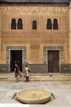 Patio del Cuarto Dorado with tourists, arabesque Moorish architecture, arched windows and