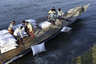 Public Works Department (PWD) of Assam labourer throwing sand bag from boat in the banks of Beki