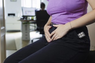 A woman has abdominal pain while working in the office. Berlin, 08.08.2024