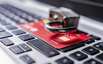 Padlock on top of credit card on laptop keyboard. Open padlock with credit card on keyboard.