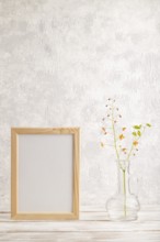 Wooden frame with orange barrenwort flowers in glass on gray concrete background. side view, copy