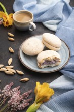 Meringues cakes with cup of coffee on a black concrete background and blue linen textile. Side