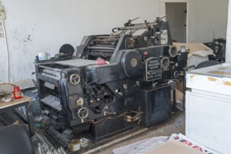 Old offset printing press in a workshop, surrounded by working materials, Heidelberg one-colour