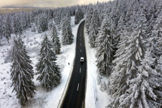 Aerial view, road leads through a snow-covered forest area near Sankt Andreasberg, 14 December 2019