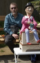 Man operating a traditional wooden jig doll dancer during a country folk event at Shottisham,