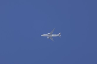 Boeing 777 jet aircraft of Qatar air cargo in flight across a blue sky, England, Unird Kingdom