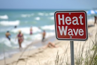 Sign with text 'Heat wave' in front of blurry sunny beach with people. KI generiert, generiert, AI