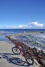 A red bicycle stands on a pier overlooking the sea on a sunny day, Tönsberg, Oslofjord, Norway,