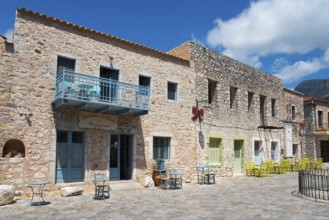 Traditional stone houses under a blue sky with balconies and green doors, Old Town, Areopoli,