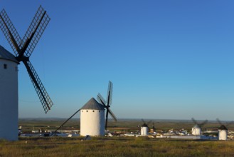 Windmills overlook a small village under a clear sky, Campo de Criptana, Ciudad Real province,