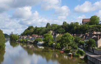 Flusslandschaft mit Uferhäusern und üppigem Grün unter einem teilweise bewölkten Himmel, Nemours am