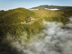 Aerial view of green hills with car road above clouds Fanal mountain, Madeira island, Portugal,