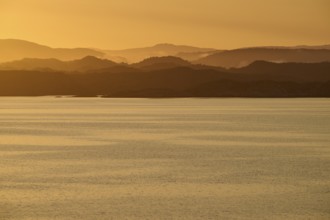 Calm atmosphere over the sea, hills and an orange sunrise, autumn, Bergen, North Sea, Norway,