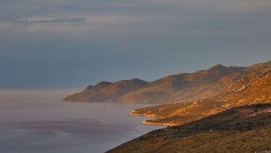 Golden morning sun illuminates a coastal landscape with mountains and sea, Mani Peninsula,