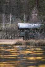 Hut on the lake with glittering water reflections at dusk, Thum See, Bad Reichenhall, Germany,