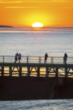 Silhouettes of several people on the pier Freilaufkanal, couple and single persons watch from a