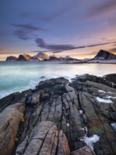 Rocky coast, snow-capped mountains in the background, Vestvågøya, Lofoten, Norway, Europe