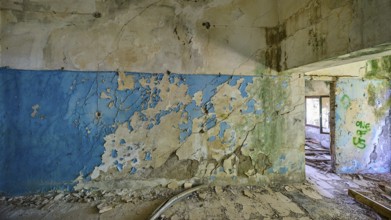 Blue and white peeling wall in a dilapidated room with partially visible graffiti, Lost Place,