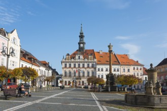 Historic town square with Baroque-style buildings and clock tower under a blue sky, town hall,