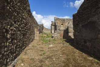 Old stone and terracotta brick wall and building structures in yard covered with brown soil and