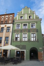 Green historic building with versatile design and next to a street café, Market Square, Poznan,