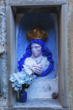 Religious blue and white with golden crown female with praying hands sculpture and silk flowers in