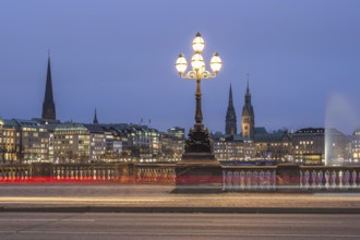 View from the Lombardsbrücke at blue hour with light traces of cars on the Inner Alster Lake with