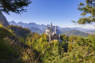 Neuschwanstein Castle framed by autumnal forests and a dramatic mountain backdrop, Schwangau,