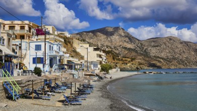 Coastal village with empty beaches and mountains in the background under a cloudy sky, Diafani,