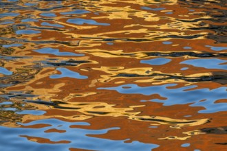 Coloured reflections and wave patterns on a river surface, Frederiksholms Canal, Copenhagen,