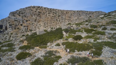 Palatia Beach, Palatia, hiking trail leads through a rocky, green landscape under a blue sky, boat