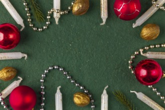 Frame made of Christmas decorations, candles, baubles, nuts on a green background, copy room