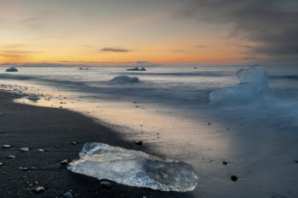 Small icebergs on the beach during sunset, long exposure, Diamond Beach, glacier lagoon Jökulsárlón