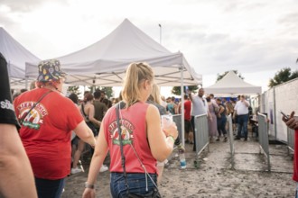 People in red T-shirts walk past white tents at a festival, Malleparty Böblingen, Germany, Europe