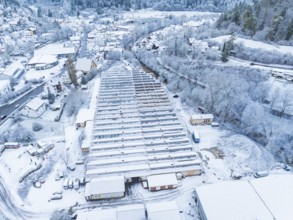 Snow-covered greenhouse complex surrounded by trees and village street in winter, Nagold, Black