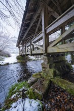 Detailed view of a wooden bridge over a stream with snow and stone substructure, Kälberbrücke,