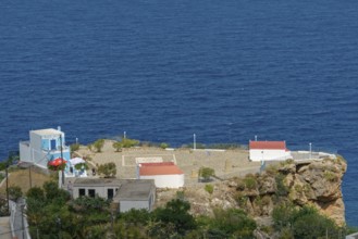 Platia Skopi with Kafe Skopi on a rocky cliff overlooking the deep blue sea and clear sky,