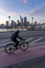 Skyline of the city centre of Frankfurt am Main, cyclist on the Ignatz-Bubis-Bridge, dusk, river