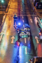 Policeman with motorbike, in rainy weather, blocking a road, police motorbike with blue light