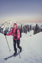 A woman's ski tour at sunrise on the Tegelberg in the Allgäu in the Ammergebirge, Bavaria, Germany,