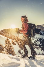 A woman's ski tour at sunrise on the Tegelberg in the Allgäu in the Ammergebirge, Bavaria, Germany,