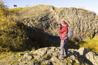 Photographer with camera and rucksack taking pictures at Hirtstein, Marienberg, Saxony, Germany,