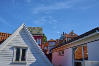 Colourful houses with red and white roofs and facades under a blue sky with soft clouds, Bergen,