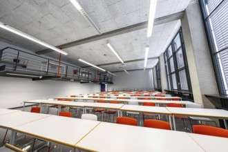 Classroom with modern furnishings, white tables and orange-coloured chairs, University of